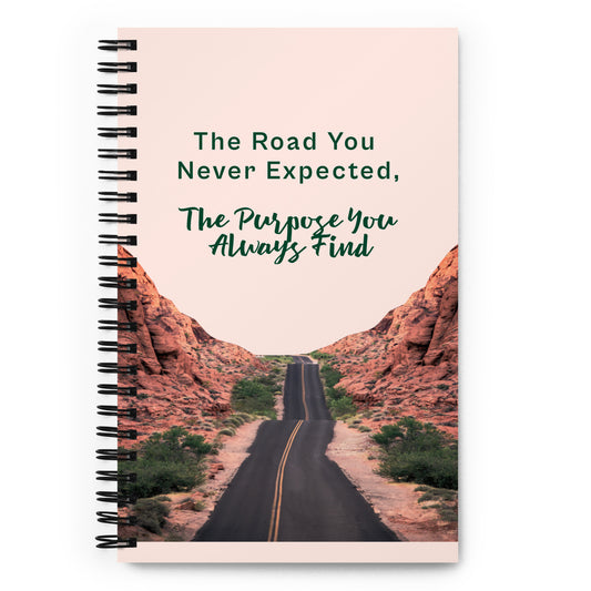 a picture of a spiral bound notebook with the words the road you never expected the purpose you always find on the top and a picture of a blacktop road with 2 yellow lines down the center going between red clay cliffs on either side of the road